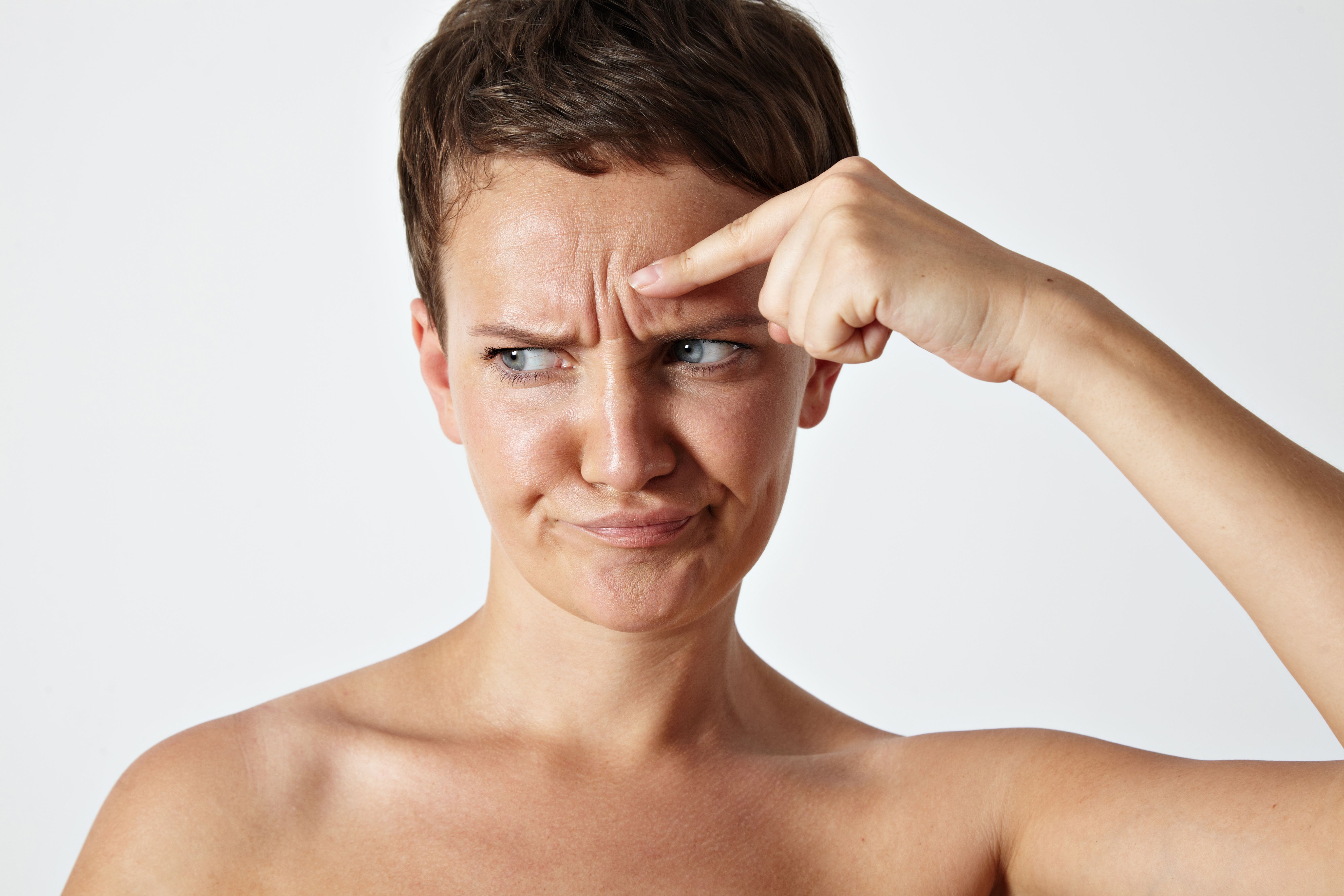 woman touching her wrinkles on a forehead with disappointed face